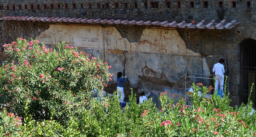 Fotoğraftaki arkeologlar, İtalya - Pompeii'de bulunan bir binada bir freski çıkarmak amacıyla çalışmaktadır. Pompeii, MS 79 yılında yakındaki Vezüv Yanardağı patladığında külle kaplanmıştır. Kül, o dönemden kalma pek çok yapı ve eseri korumuştur.