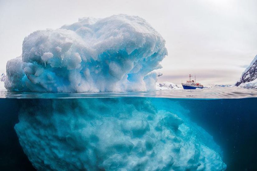 Antarktika'da yer alan bir aysberg buzulu ve sualtı görünümü. Fotoğrafın sağ tarafındaki 3.000 tonluk geminin ne kadar küçük göründüğüne dikkat ediniz. Ancak bu fotoğraf sadece bir photoshop. Bir kimyager olan ve aynı zamanda fotoğrafçılık yapan Rick Do Boisson, gemi kameradan 600 metre uzaktayken, 6 metre uzunluğundaki buzdağını birleştirerek bu fotoğrafı elde etti. Fotoğraf gerçek olmasa da buzdağları, devasa büyüklüktedir.