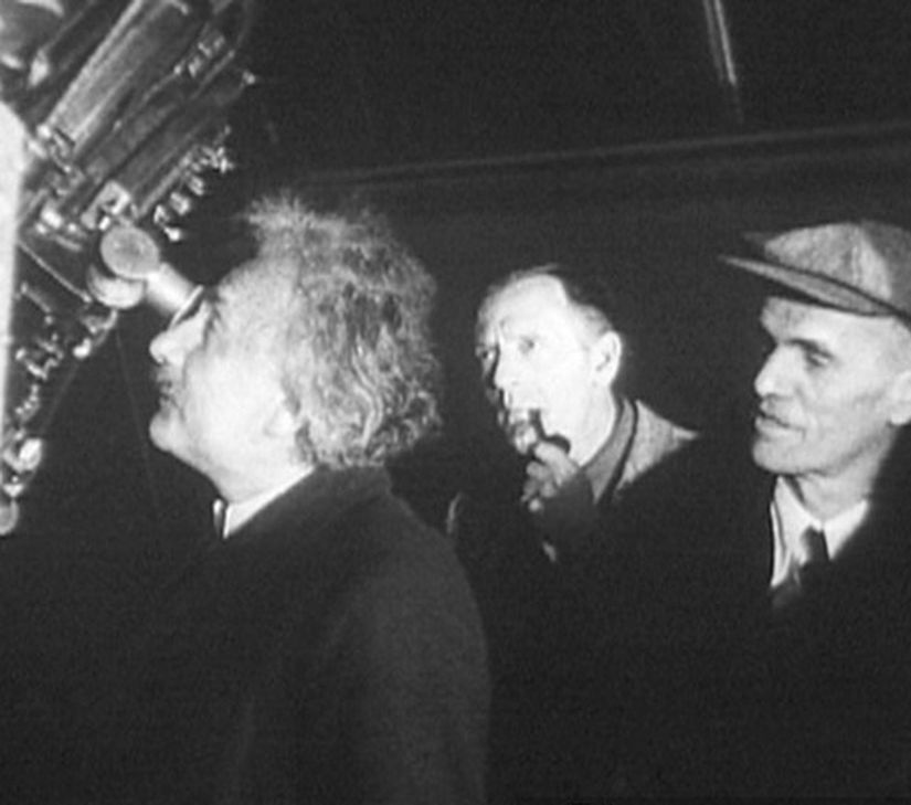 Einstein, Mount Wilson Gözlemevi'nde Hooker Teleskobu ile gözlem yapıyor. Sağda ise ağzında purosuyla onu meraklı bakışlarla izleyen Edwin Hubble.