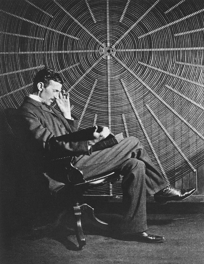 Tesla, East Houston St. sitting in front of a spiral coil used in wireless power experiments in his lab. Who is Nikola Tesla? What Did He Invent? Myths and Facts!