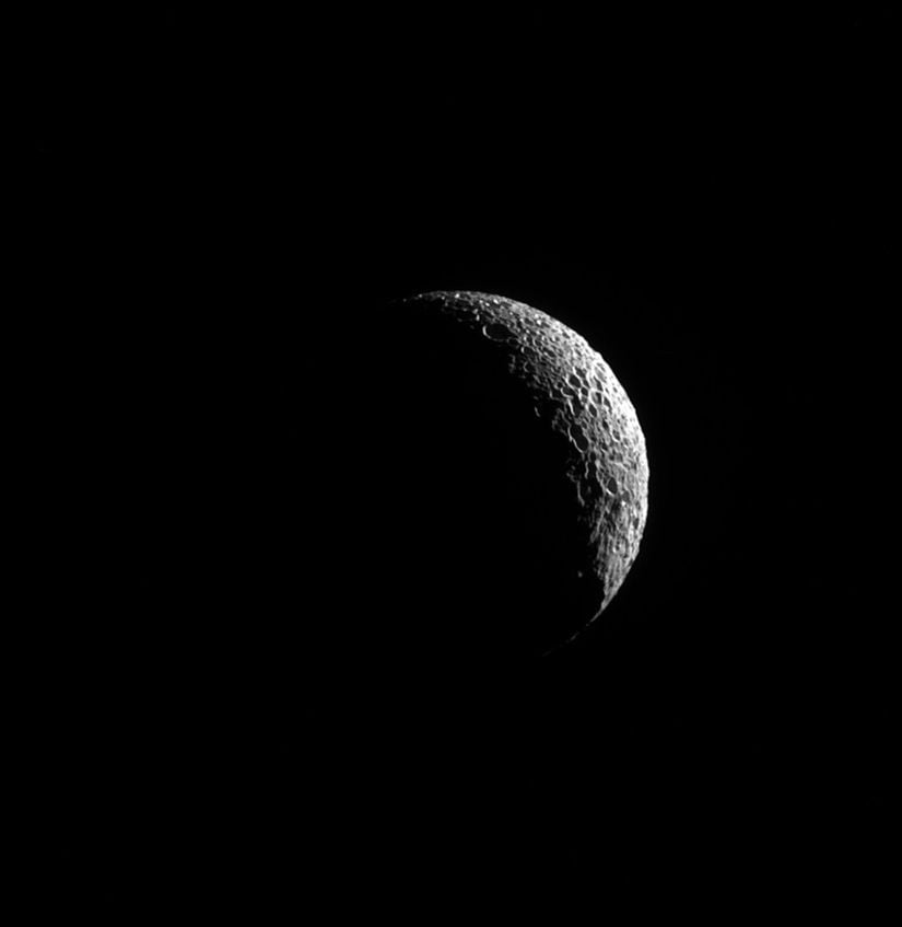 Mimas'ın bu görüntüsündeki krater çukurlarının göstergesi olan derin gölgeler, uydunun şiddet dolu geçmişini gözler önüne sermektedir.